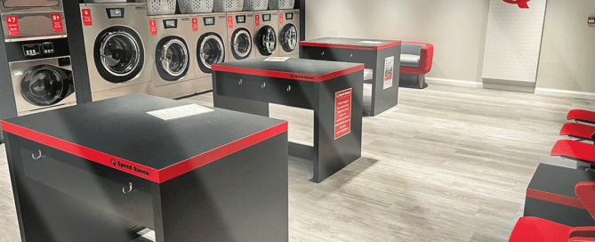 A Speed Queen laundry room featuring a table and chairs, providing a functional space for folding clothes and organizing laundry tasks.