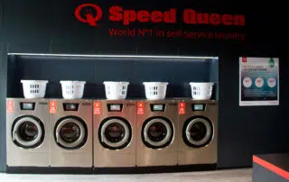 A row of Speed Queen washing machines showcasing their sleek design and advanced features in a modern laundry setting.